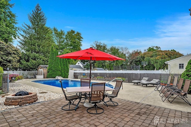 view of swimming pool with an outdoor fire pit, a fenced backyard, a patio area, a storage unit, and an outdoor structure