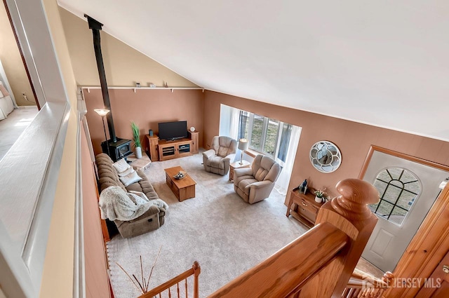 living room with a wood stove, carpet, and vaulted ceiling