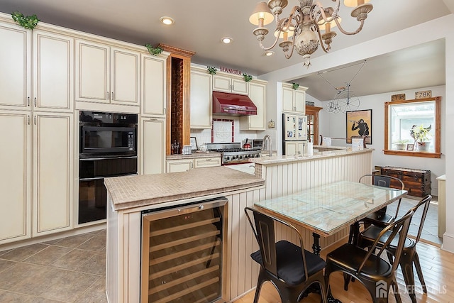 234 W Church St, Gloucester Twp, NJ 08012 - kitchen featuring cream cabinets, under cabinet range hood, a kitchen island with sink, and wine cooler