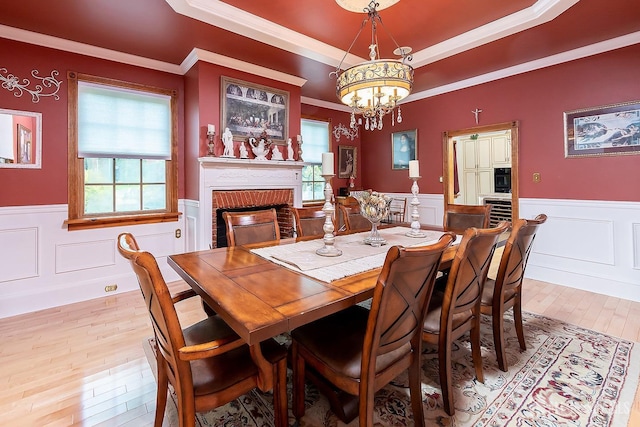 234 W Church St, Gloucester Twp, NJ 08012 - dining area with an inviting chandelier, a fireplace, a raised ceiling, a wainscoted wall, and light wood-style floors