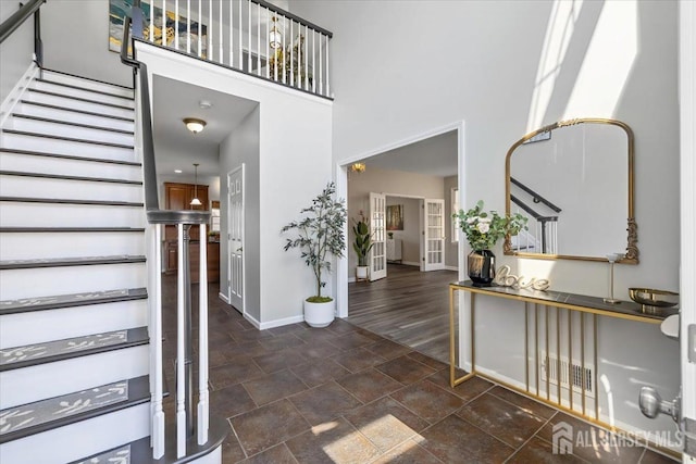 entryway with a towering ceiling and french doors