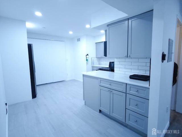 kitchen with recessed lighting, gray cabinets, light countertops, and decorative backsplash