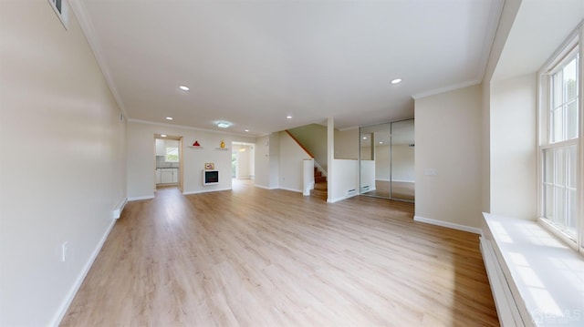 unfurnished living room with crown molding, a fireplace, light hardwood / wood-style floors, and baseboard heating