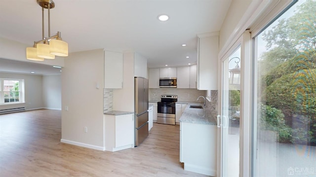 kitchen with light hardwood / wood-style flooring, appliances with stainless steel finishes, pendant lighting, decorative backsplash, and white cabinets