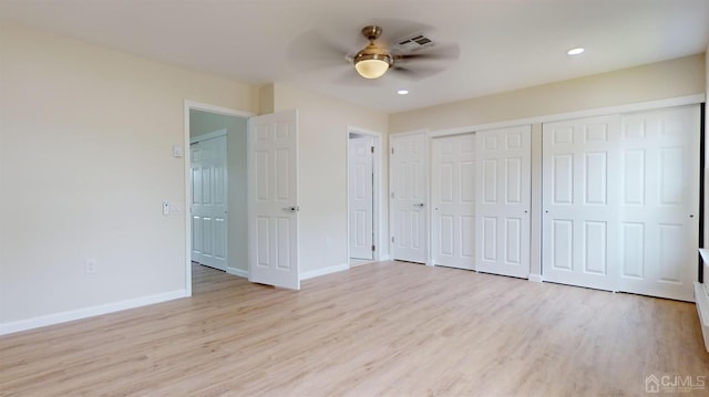 unfurnished bedroom with ceiling fan, light hardwood / wood-style floors, and two closets