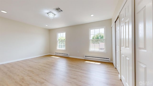 unfurnished room with a baseboard radiator and light wood-type flooring