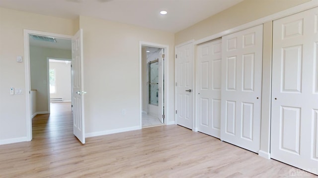 unfurnished bedroom with a baseboard heating unit, ensuite bath, and light hardwood / wood-style flooring