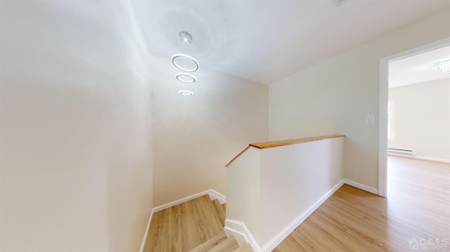 stairs featuring wood-type flooring and baseboard heating