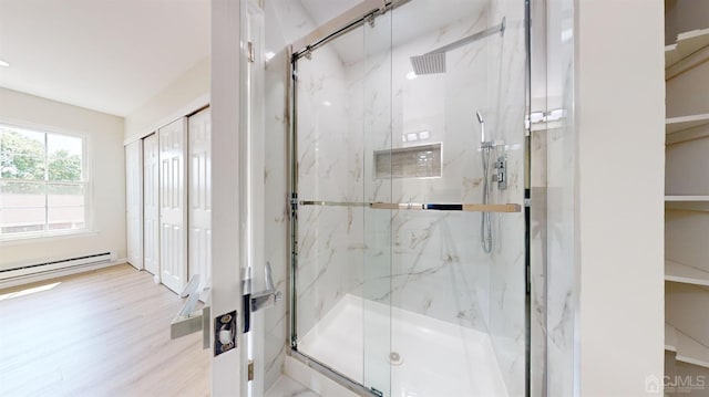 bathroom featuring a shower with shower door, wood-type flooring, and baseboard heating