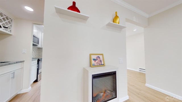 interior space featuring crown molding, baseboard heating, and light hardwood / wood-style floors