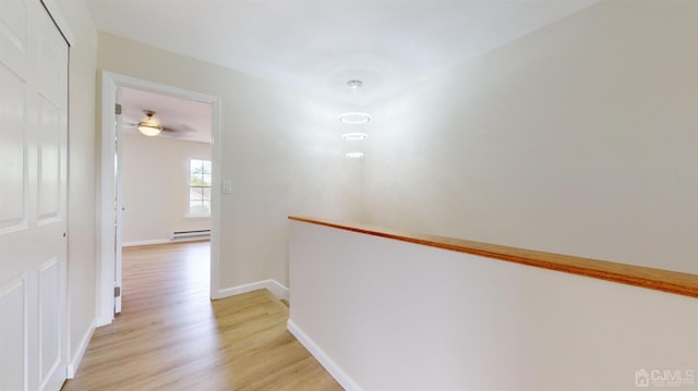 hall with baseboard heating and light hardwood / wood-style flooring