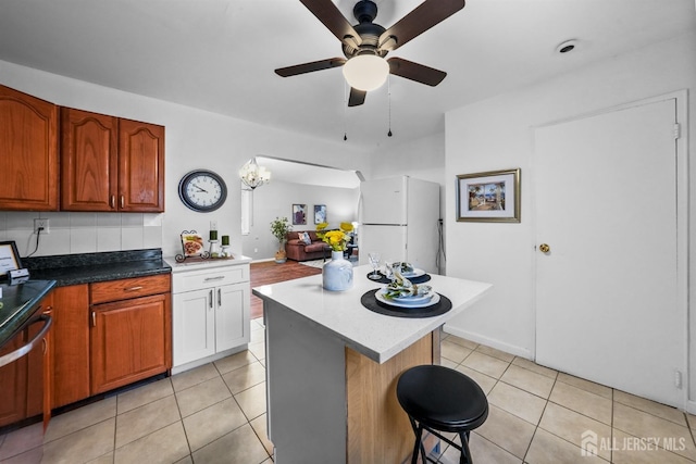 kitchen featuring light tile patterned floors, a kitchen breakfast bar, a center island, and white refrigerator