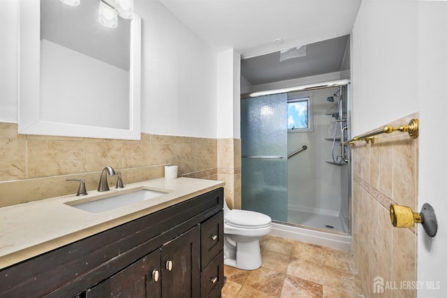 bathroom with vanity, toilet, a shower with door, and tile walls