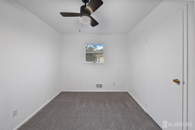 empty room featuring ceiling fan and dark colored carpet