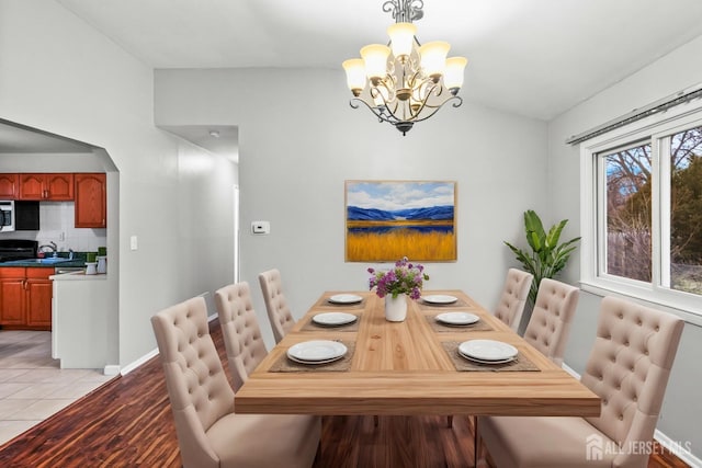 dining room featuring a notable chandelier, vaulted ceiling, and light hardwood / wood-style floors