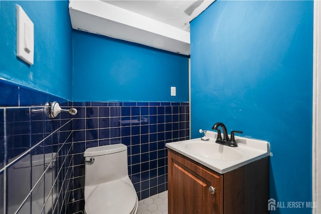 bathroom with vanity, toilet, and tile walls