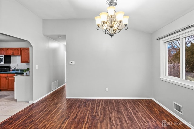 unfurnished dining area with an inviting chandelier, sink, light hardwood / wood-style floors, and lofted ceiling