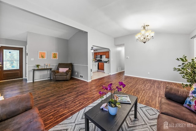 living room featuring hardwood / wood-style floors, vaulted ceiling, and a chandelier