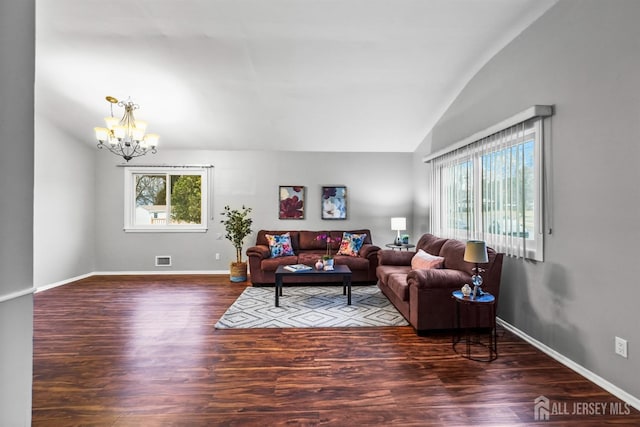 living room with dark wood-type flooring, vaulted ceiling, and a chandelier