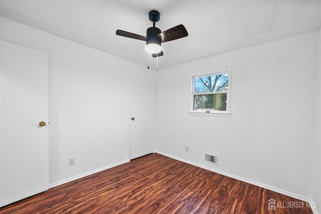 spare room with dark wood-type flooring and ceiling fan