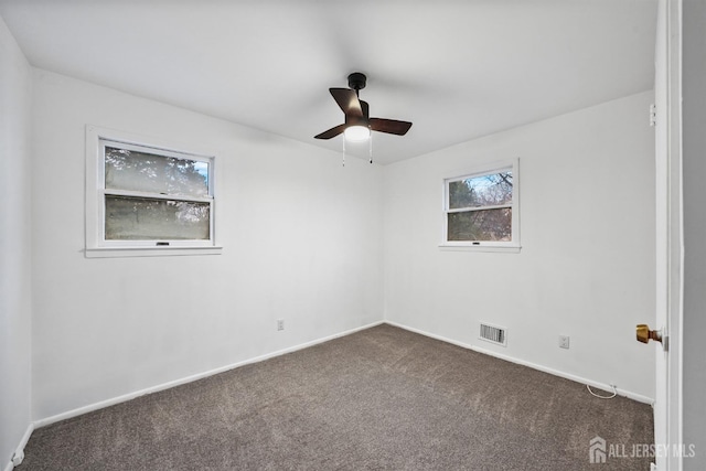 spare room featuring dark carpet and ceiling fan