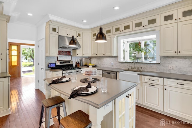 369 N Main St, Milltown, NJ 08850 - kitchen featuring stainless steel appliances, under cabinet range hood, dark countertops, a kitchen breakfast bar, and ornamental molding