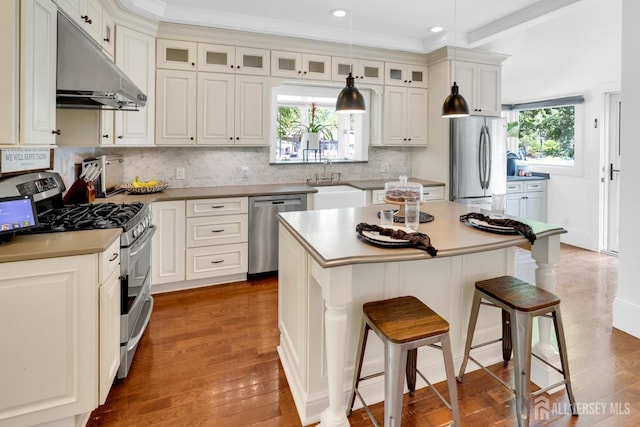 369 N Main St, Milltown, NJ 08850 - kitchen with stainless steel appliances, under cabinet range hood, a breakfast bar, wood finished floors, and ornamental molding