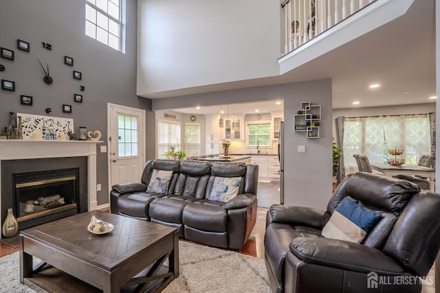 108 Jared Dr, North Brunswick, NJ 08902 - living area featuring wood finished floors, a towering ceiling, plenty of natural light, a glass covered fireplace, and recessed lighting