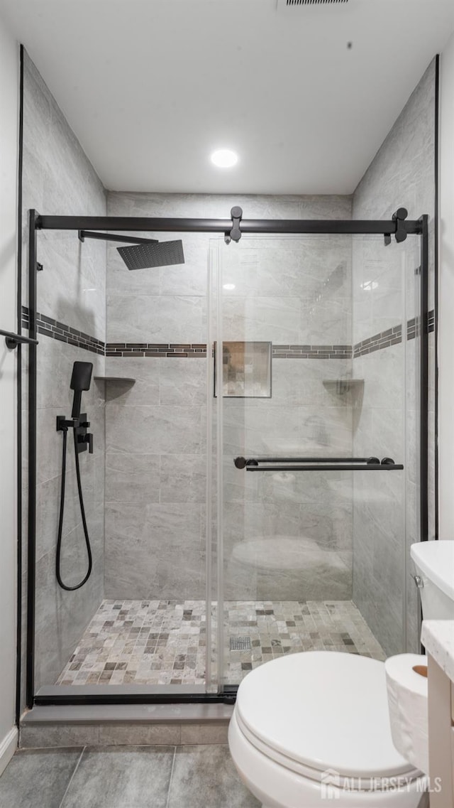 bathroom with toilet, a stall shower, and vanity