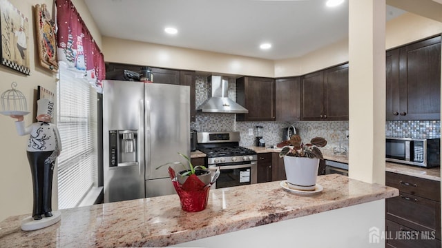 kitchen featuring tasteful backsplash, appliances with stainless steel finishes, dark brown cabinets, light stone countertops, and wall chimney exhaust hood