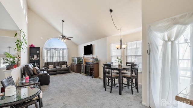 living area featuring high vaulted ceiling, light colored carpet, plenty of natural light, and ceiling fan with notable chandelier