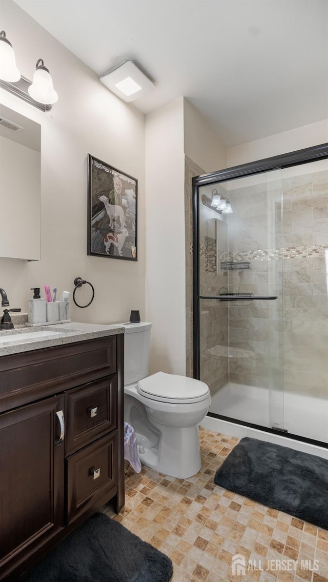 bathroom featuring toilet, a shower stall, visible vents, and vanity