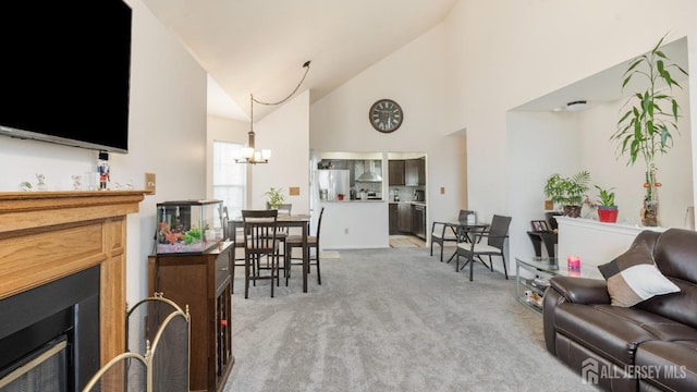 living area with high vaulted ceiling, a fireplace, a chandelier, and light colored carpet