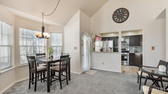 dining area with a chandelier, a wealth of natural light, light colored carpet, and baseboards