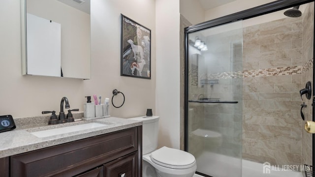 full bathroom with toilet, a stall shower, and vanity