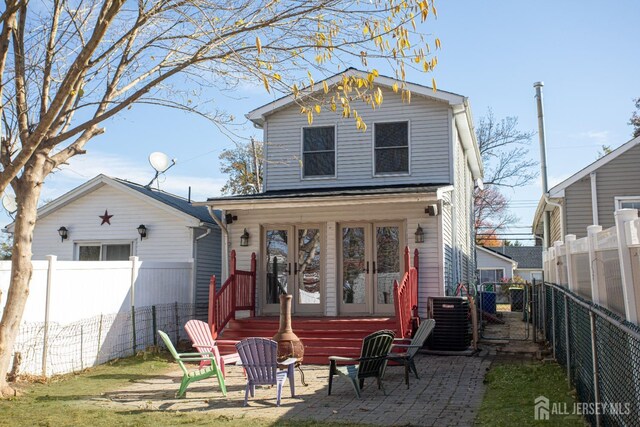 rear view of property featuring french doors, cooling unit, and a patio area