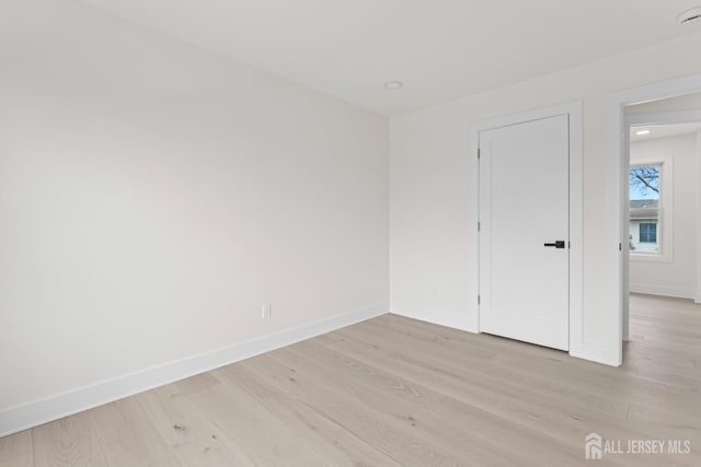 unfurnished room featuring baseboards and light wood-type flooring