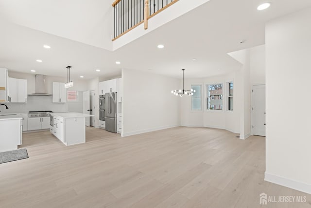 unfurnished living room featuring a sink, light wood-type flooring, baseboards, recessed lighting, and a notable chandelier