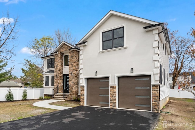 traditional home with an attached garage, fence, stone siding, and aphalt driveway