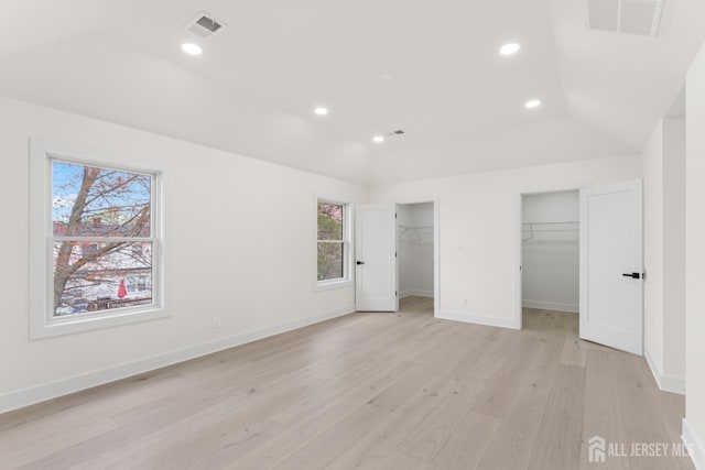 unfurnished bedroom with light wood-style flooring, visible vents, vaulted ceiling, and multiple windows