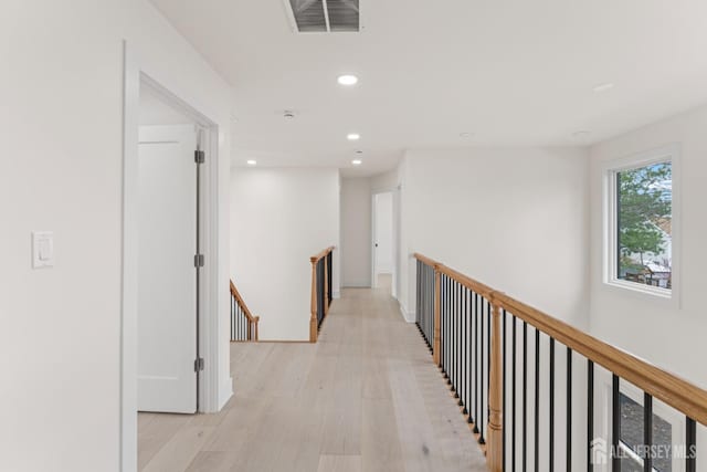 corridor with recessed lighting, light wood-style floors, visible vents, and an upstairs landing