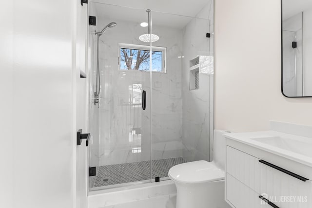 bathroom featuring a marble finish shower, vanity, and toilet