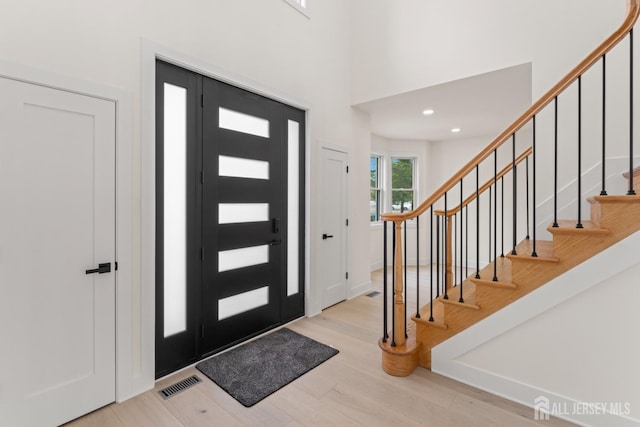 foyer with stairway, wood finished floors, and visible vents
