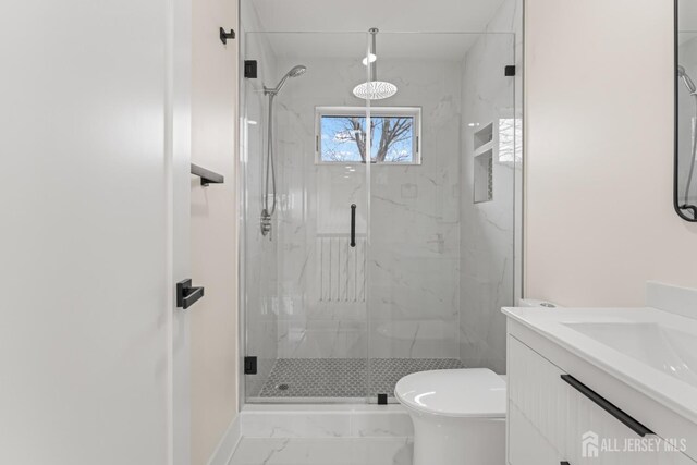 bathroom featuring marble finish floor, toilet, vanity, and a marble finish shower