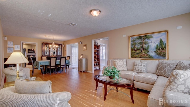 741-B Nautilus Ct Unit B, Monroe, NJ 08831 - living room with a chandelier, light wood-style flooring, and a textured ceiling