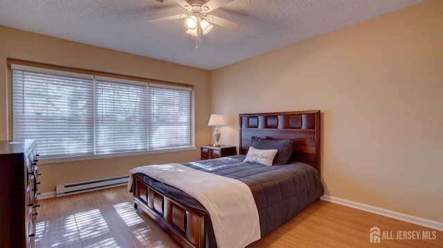 741-B Nautilus Ct Unit B, Monroe, NJ 08831 - bedroom featuring a baseboard heating unit, baseboards, light wood finished floors, a textured ceiling, and a ceiling fan