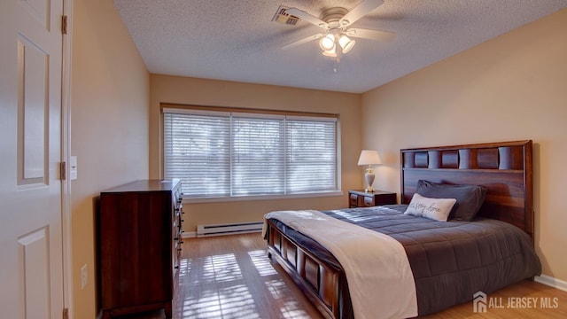 741-B Nautilus Ct Unit B, Monroe, NJ 08831 - bedroom with a baseboard radiator, a textured ceiling, wood finished floors, a ceiling fan, and baseboards