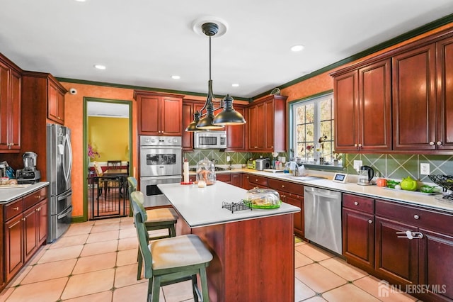 kitchen with a breakfast bar, a center island, hanging light fixtures, appliances with stainless steel finishes, and backsplash