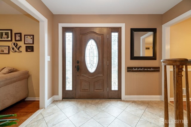 foyer entrance featuring light tile patterned floors, plenty of natural light, and baseboards