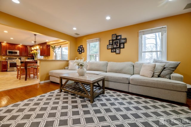 living area featuring recessed lighting, a healthy amount of sunlight, visible vents, and wood finished floors